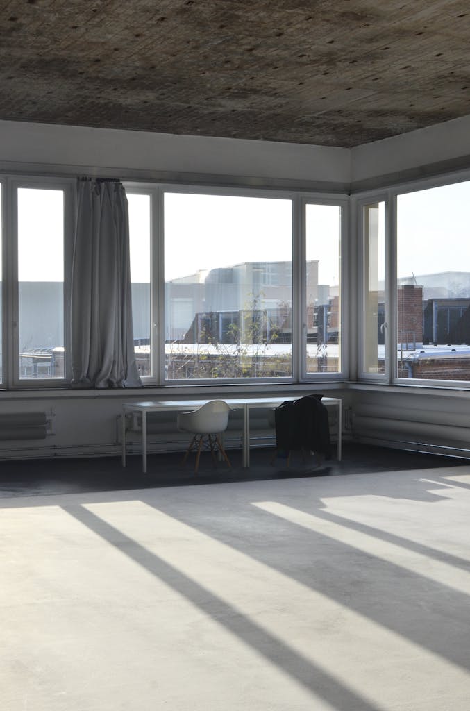 Spacious studio with table at window with concrete flooring. 