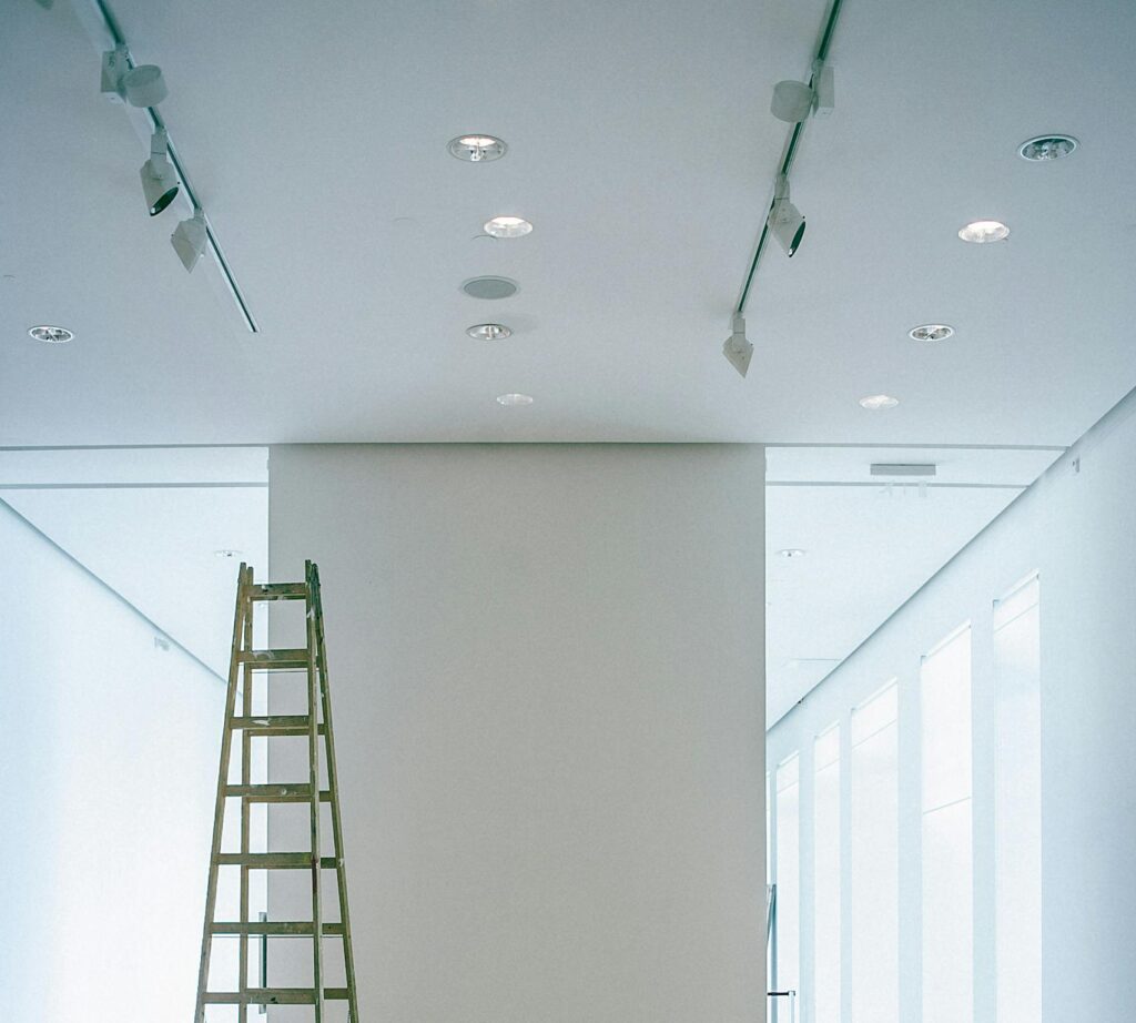 Empty corridor with ladder and lamps on ceiling