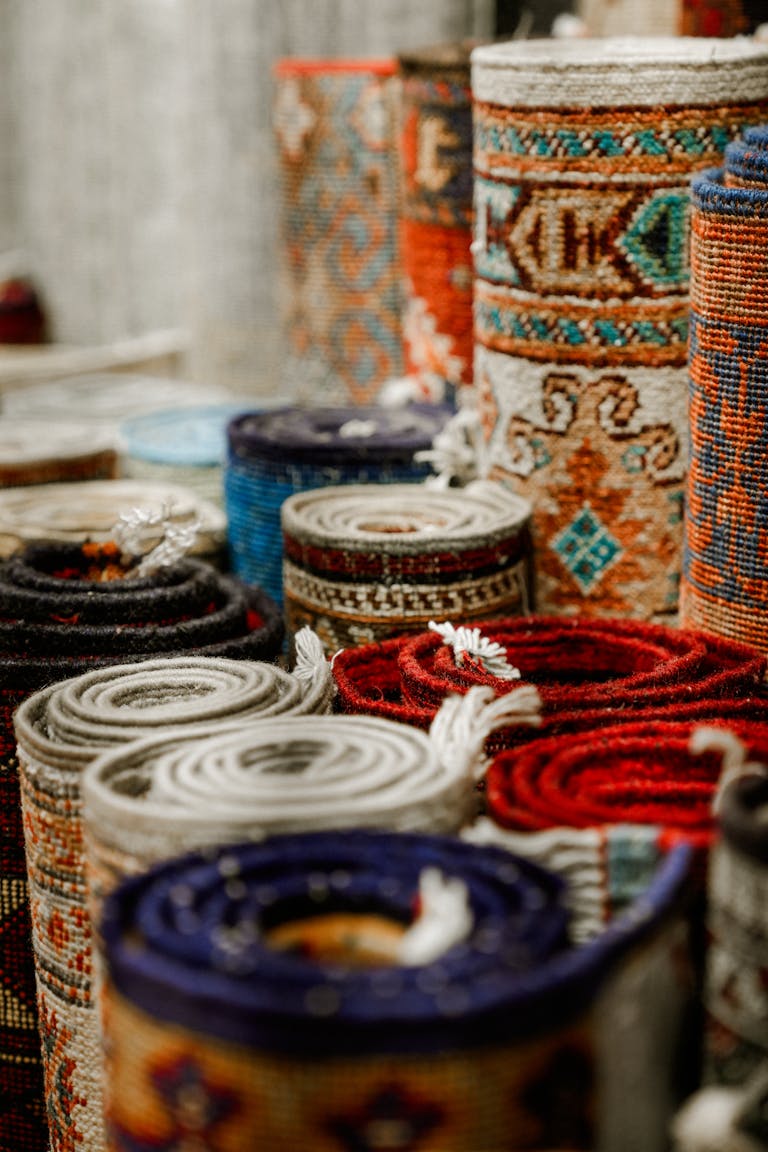 A variety of rolled colorful rugs showcasing intricate traditional patterns.