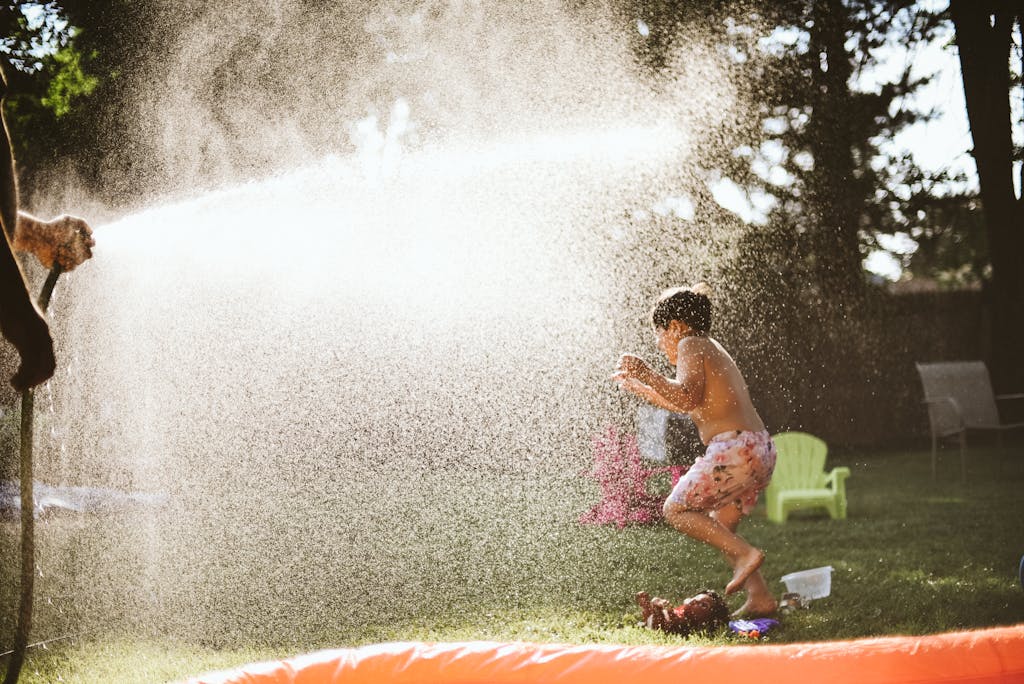 Boy enjoying water spray in backyard on a sunny summer day, capturing fun and joy.